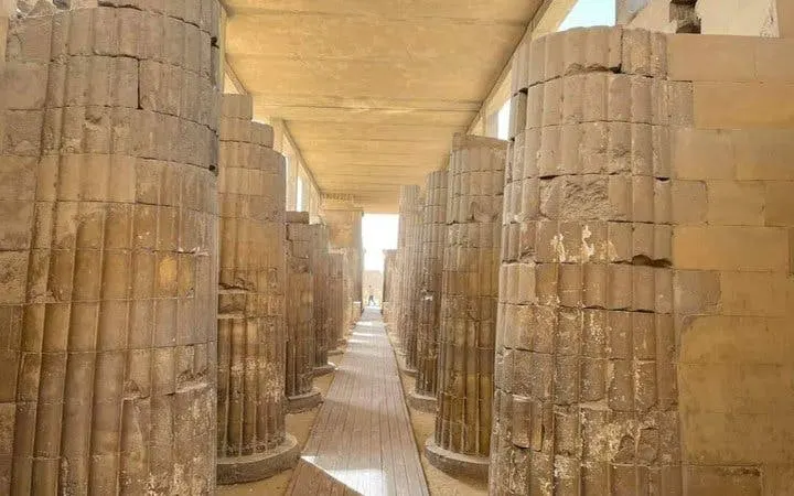 Ancient stone columns in an Egyptian model village, part of a guided tour.