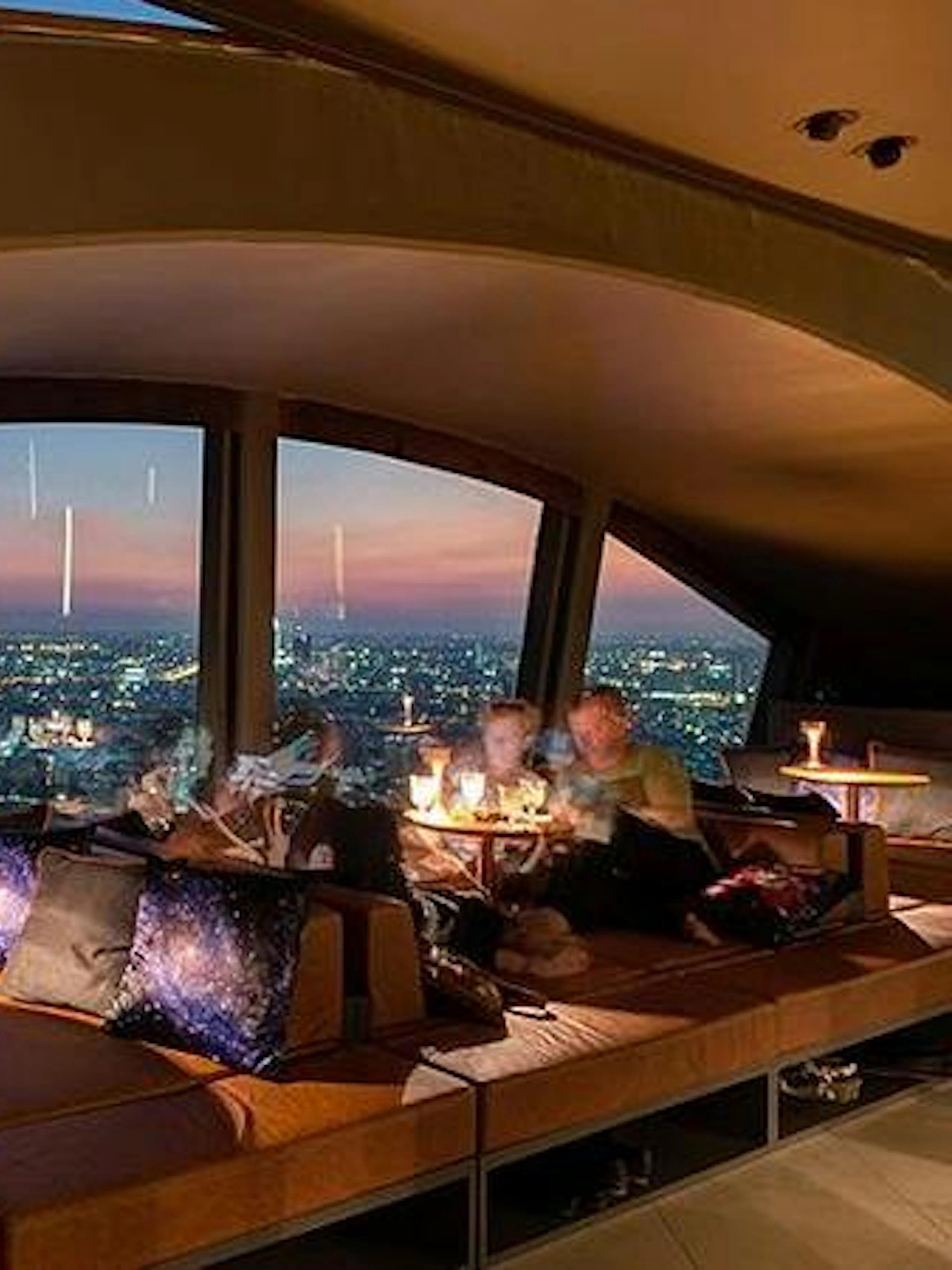 Skyline view from Vertigo TOO Sky Bar, Bangkok, with patrons dining at sunset.