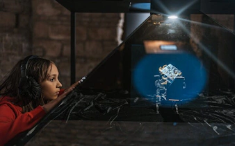 Person observing holographic display at Time Machine Budapest exhibition.