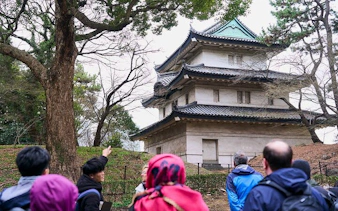 Visitors on a guided tour near a historic building at Tokyo Imperial Palace.