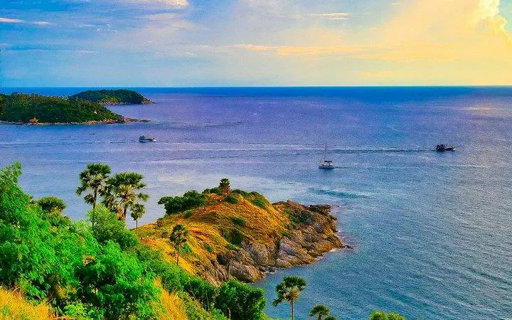 Phuket coastline view with lush greenery and boats on the sea.