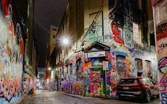 Graffiti-covered laneway in Melbourne at night, part of self-guided audio walking tour.