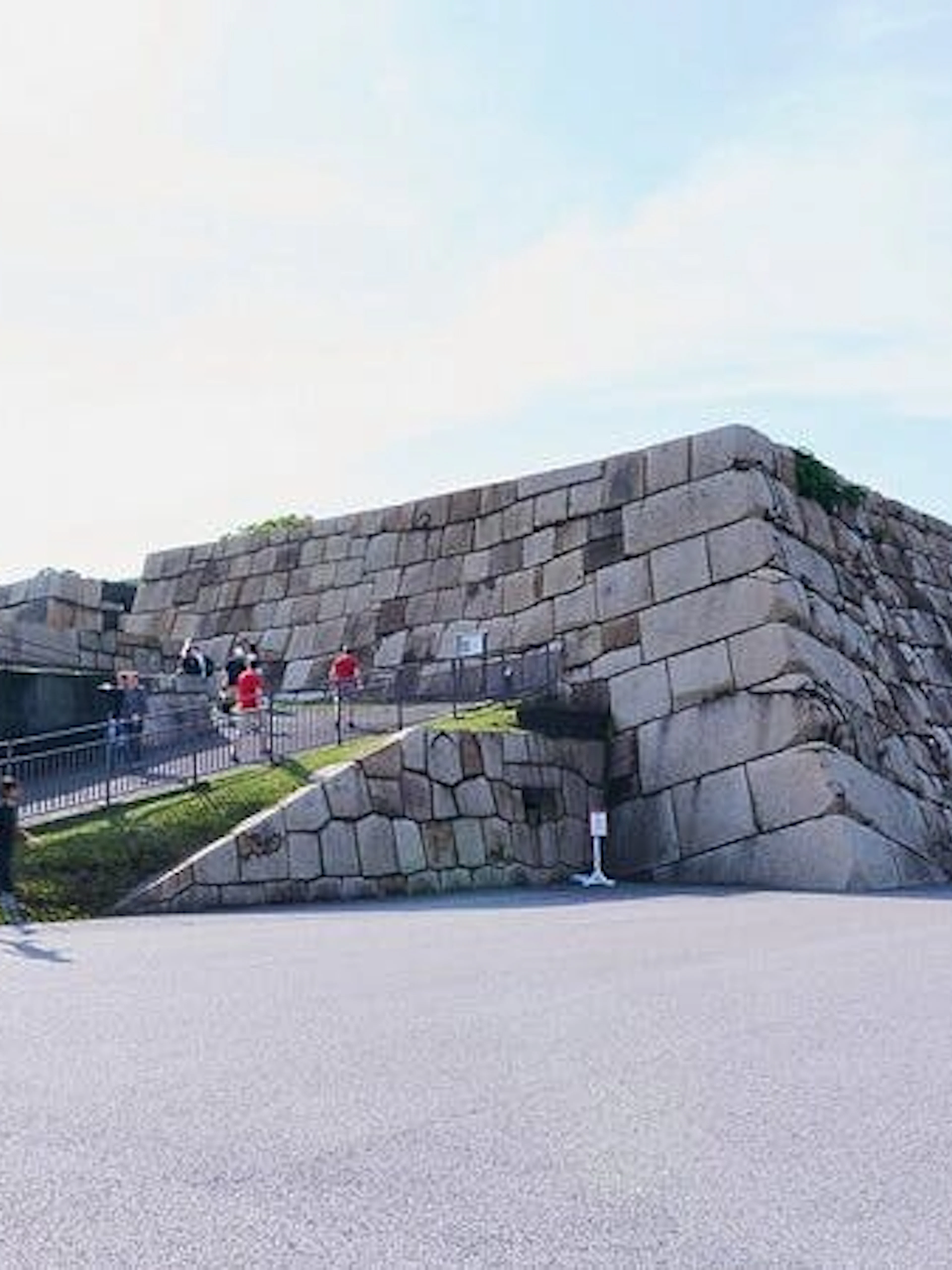 Visitors walking near the stone walls of Tokyo Imperial Palace during a guided tour.