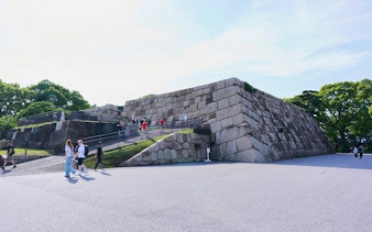 Visitors walking near the stone walls of Tokyo Imperial Palace during a guided tour.