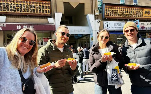 Visitors enjoying street food at Tsukiji Fish Market, Tokyo.