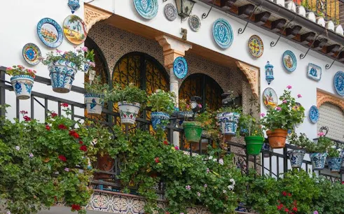 Balcony with colorful ceramic plates and potted plants in Granada, Spain.
