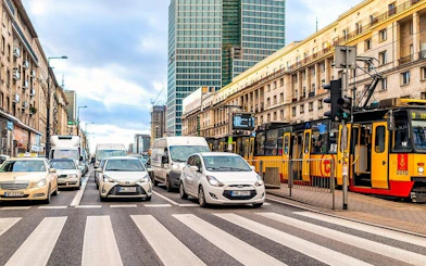 Warsaw street scene with cars, tram, and high-rise buildings in Muranów district.
