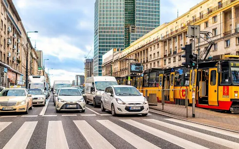 Warsaw street scene with cars, tram, and high-rise buildings in Muranów district.