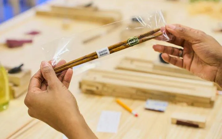 Chopsticks in packaging at Kyoto Arashiyama workshop table with tools.