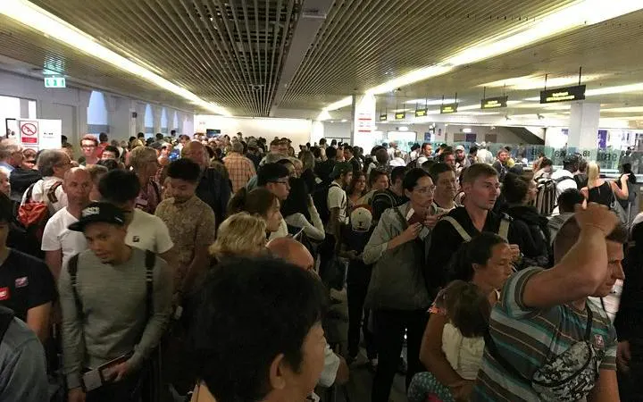 Crowded immigration area at Phuket International Airport with travelers waiting in line.