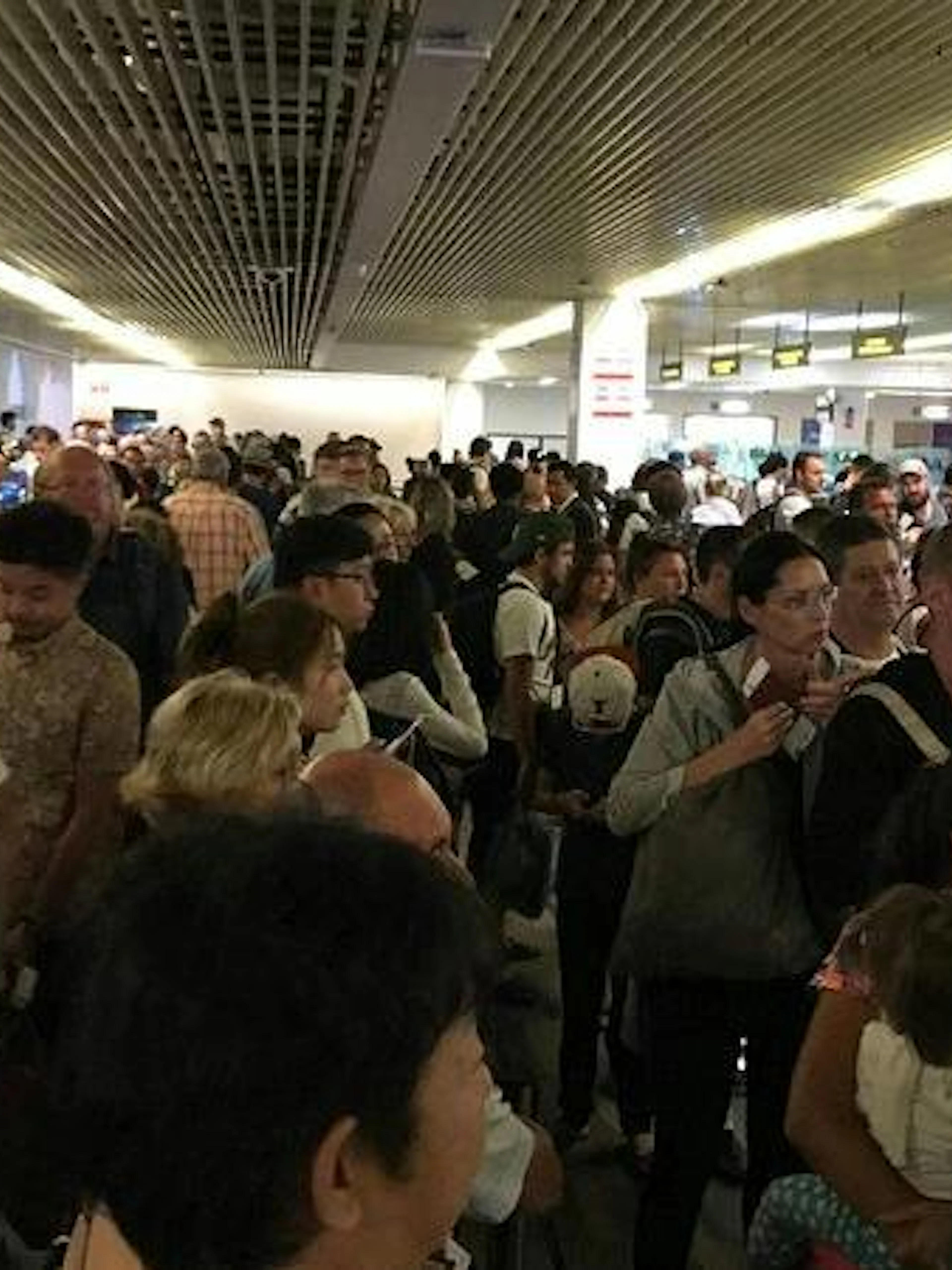 Crowded immigration area at Phuket International Airport with travelers waiting in line.