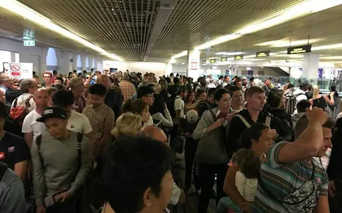 Crowded immigration area at Phuket International Airport with travelers waiting in line.
