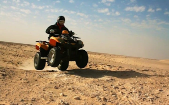 ATV quad bike rider in desert near Sharm El Sheikh during sunset safari.