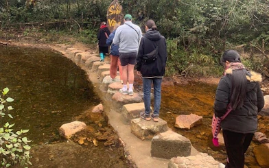 Tourists crossing stepping stones on a stream in Sa Pa during a motorbike tour.