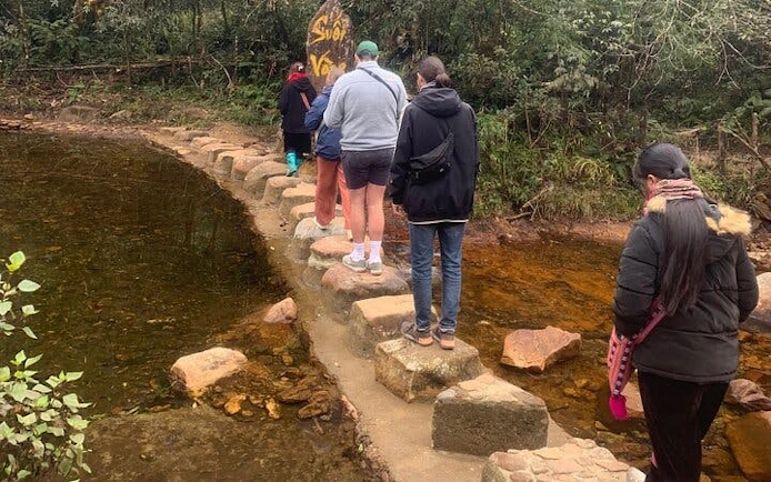 Tourists crossing stepping stones on a stream in Sa Pa during a motorbike tour.