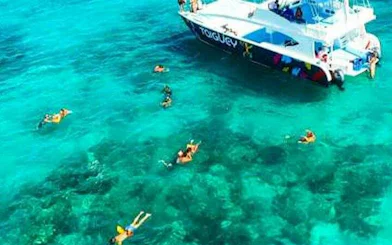 Snorkelers near a private party boat in clear Punta Cana waters.