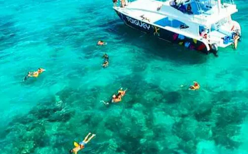 Snorkelers near a private party boat in clear Punta Cana waters.