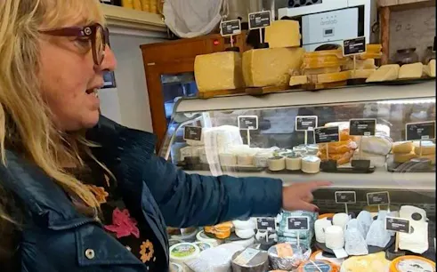 Person pointing at cheese display in a shop during Lisbon Food and Wine Walking Tour in Mouraria.