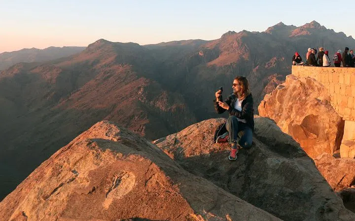 Hiker enjoying sunrise view from Moses Mountain near Saint Catherine Monastery, Sinai Peninsula.
