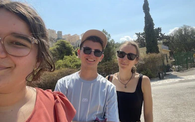 Three people enjoying a sunny day in Athens with ancient ruins in the background.