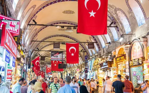 Grand Bazaar in Istanbul with Turkish flags and bustling shoppers.