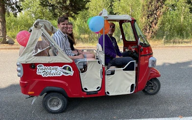 Tuk Tuk with tourists on Tuscany wine tour, featuring local guide and colorful balloons.