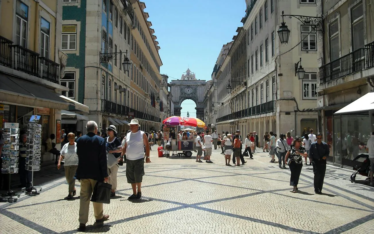 Lisbon's Rua Augusta Arch with people walking in Baixa district during a self-guided audio tour.