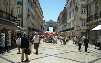 Lisbon's Rua Augusta Arch with people walking in Baixa district during a self-guided audio tour.