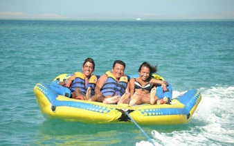 Three people enjoying a banana boat ride on the sea in Sharm El Sheikh.
