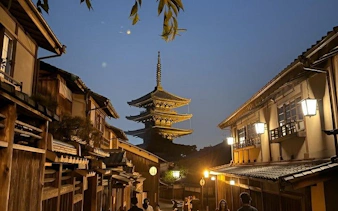 Pagoda in Kyoto's Gion district at dusk, surrounded by traditional wooden buildings.