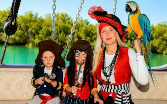 Pirate-themed boat trip in Alanya with children in costumes and a parrot on deck.