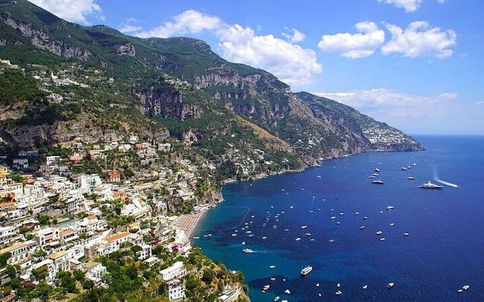 Amalfi Coast view with hillside village and boats on the sea, Italy.