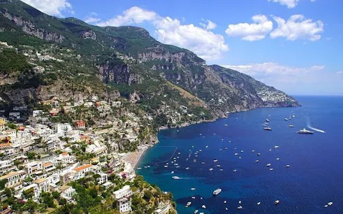 Amalfi Coast view with hillside village and boats on the sea, Italy.