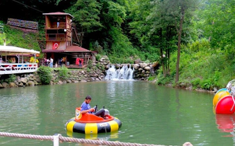 Child enjoying bumper boat ride on a lake with waterfall in Sapanca, Turkey.