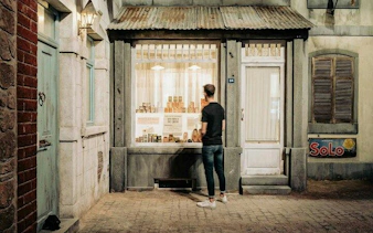 Man observing a historical storefront display at Bastogne War Museum during Battle of the Bulge tour.