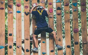 Participant climbing a wooden wall at Phoenix Zipline Adventure Park, Chiang Mai.