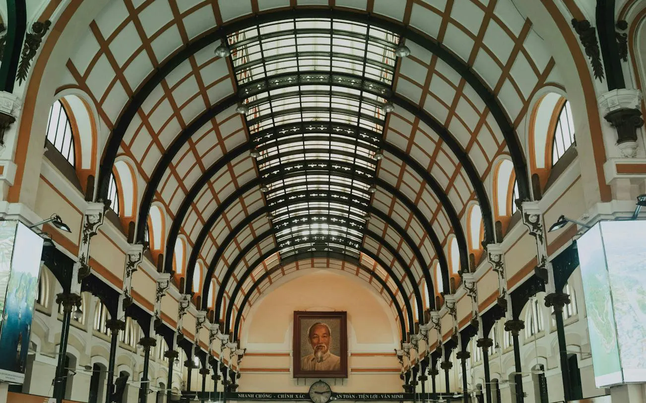 Interior of Saigon Central Post Office, Ho Chi Minh City, featuring arched ceiling and portrait.