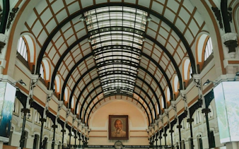 Interior of Saigon Central Post Office, Ho Chi Minh City, featuring arched ceiling and portrait.