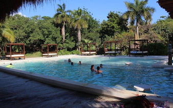 Poolside relaxation at Isla Mujeres beach club with cabanas and palm trees.
