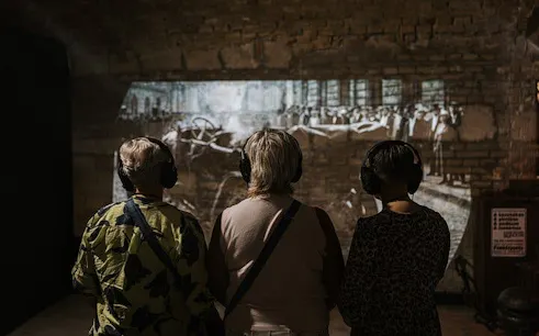 Visitors with headphones view historical projection at Time Machine Budapest exhibition.