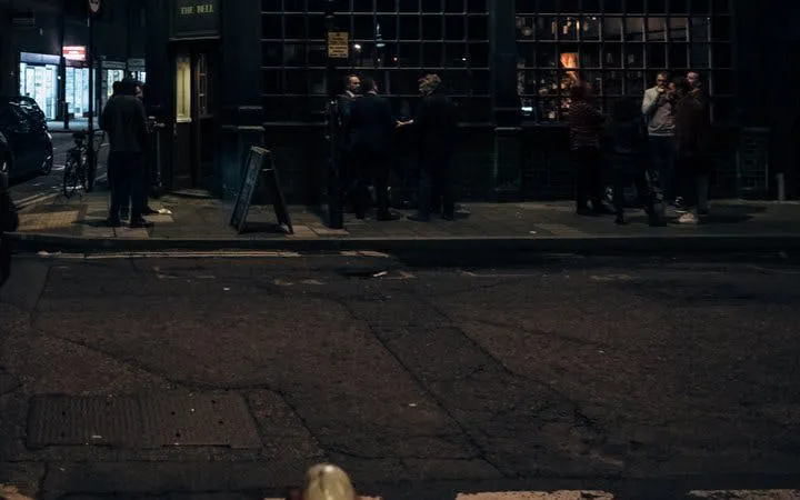 Street scene in Bath at night with people gathered outside a historic pub for a ghost walk.