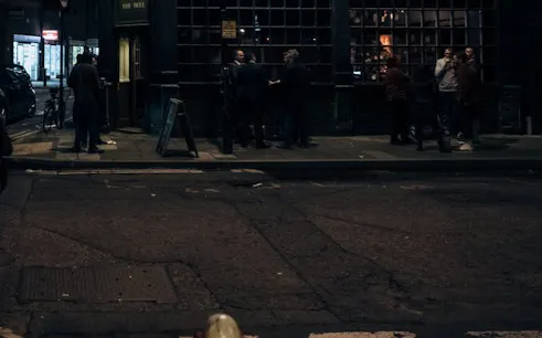 Street scene in Bath at night with people gathered outside a historic pub for a ghost walk.