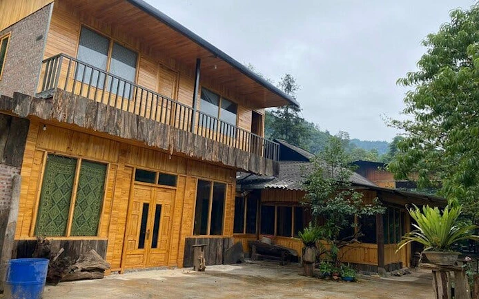 Homestay exterior in Ta Phin Village, Sapa, featuring wooden architecture and surrounding greenery.