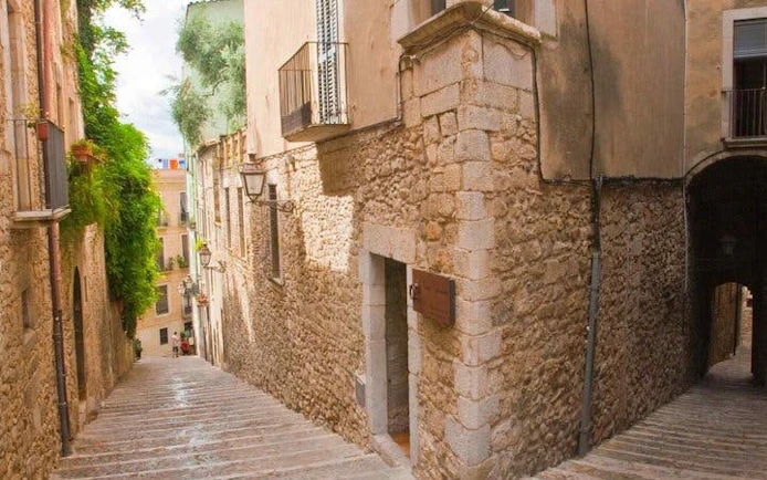 Girona stone alleyway with historic buildings on self-guided walking tour route.
