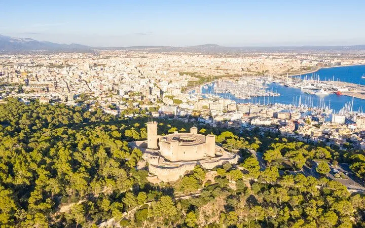 Bellver Castle aerial view, surrounded by forest, overlooking Palma de Mallorca and harbor.