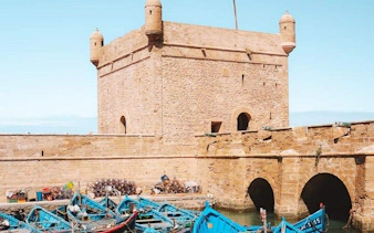 Essaouira harbor with blue fishing boats and historic fortress walls.