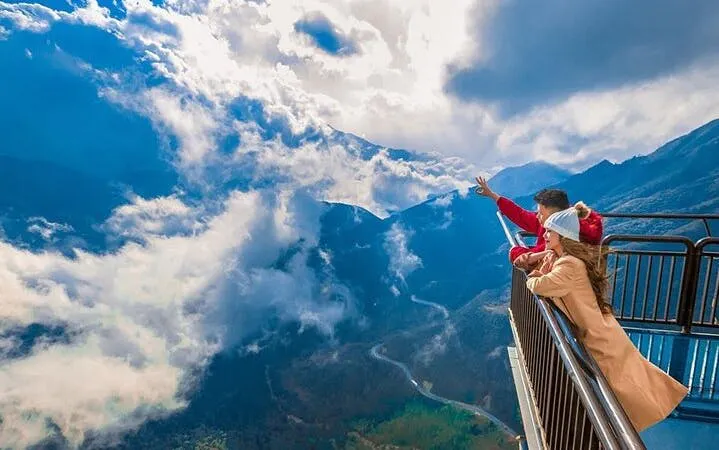 Couple on Sapa motorbike tour viewing mountains and clouds from a scenic overlook.