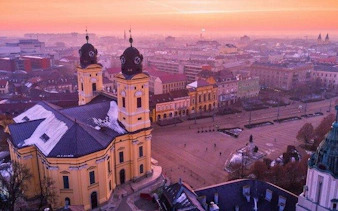 Debrecen cityscape with Great Reformed Church at sunrise, part of self-guided audio walking tour.