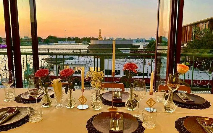 Fine dining setup overlooking Chao Phraya River at sunset, Bangkok.