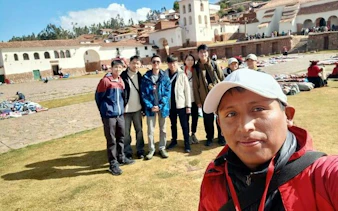 Group of tourists at Chinchero archaeological site, Sacred Valley, with colonial church in background.